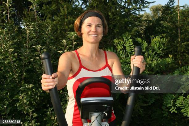 Yoga, woman on a crosstrainer in the garden -