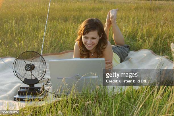 Fernsehen, digitales Fernsehen DVB-T, Frau liegt auf der Wiese und guckt auf einem Laptop Fernsehen -