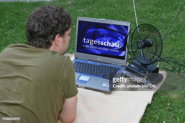 Fernsehen, digitales Fernsehen DVB-T, Mann liegt auf der Wiese und guckt auf seinem Laptop Fernsehen -