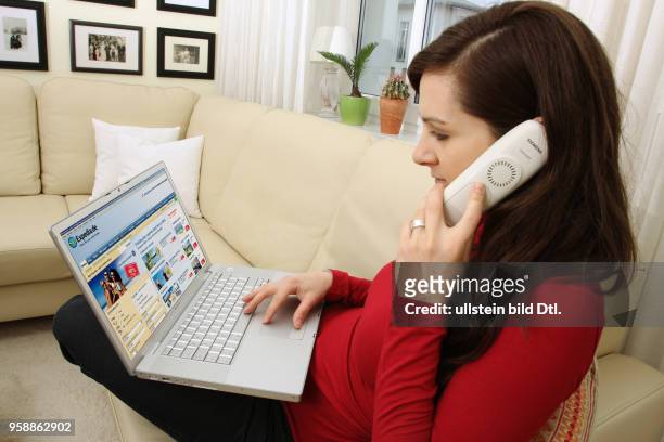 Woman with laptop sitting on the sofa is surfing in the internet on the homepage of the online travel agency expedia -