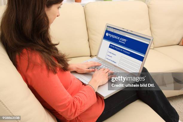 Woman with laptop sitting on the sofa is surfing in the internet on the internet platform myspace -
