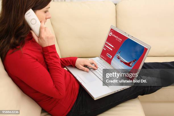 Woman with laptop sitting on the sofa is surfing in the internet on the homepage of the AirBerlin airline -