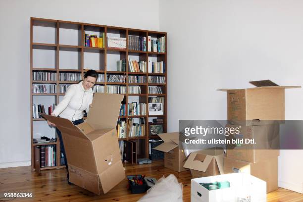 Germany Berlin - moving the apartment, young woman is packing books into boxes -