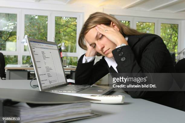 Young woman is working at an apple laptop and is tired -