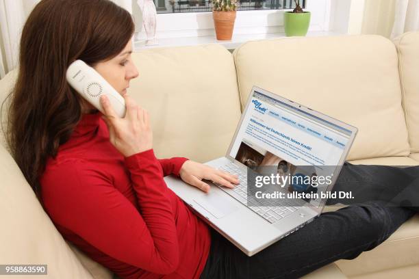 Woman with laptop sitting on the sofa is surfing in the internet on the homepage of TeamBank AG with the consumer credit easyCredit -