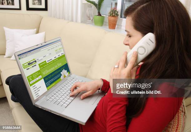 Woman with laptop sitting on the sofa is surfing in the internet on the homepage of the pharmacy DocMorris -