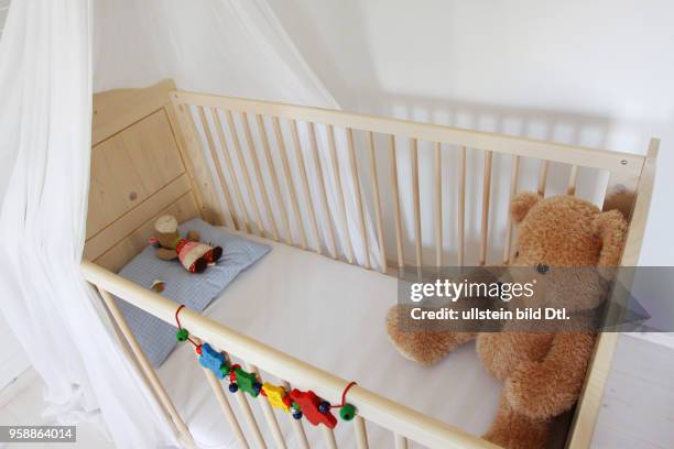 Ein Kinderbett mit einem Teddy steht in einem Kinderzimmer