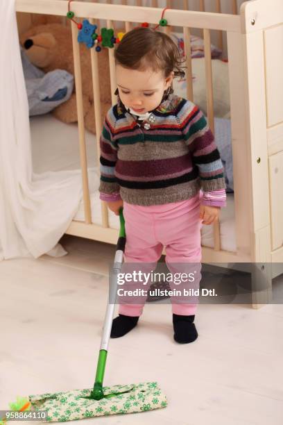 Ein Kleinkind putzt den Fussboden in seinem Kinderzimmer