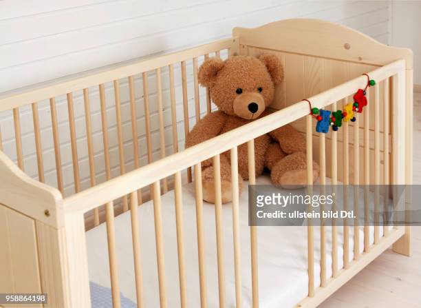 Ein Kinderbett mit einem Teddy steht in einem Kinderzimmer