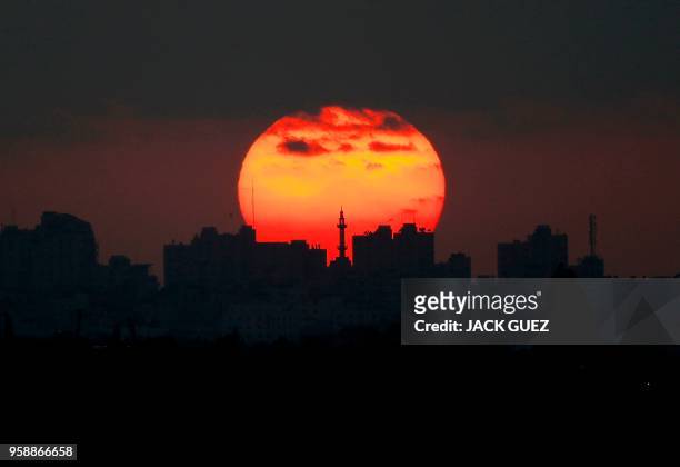 Picture taken on May 15 from the southern Israeli kibbutz of Nahal Oz shows the sun setting over the skyline of Gaza City.