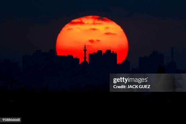 Picture taken on May 15 from the southern Israeli kibbutz of Nahal Oz shows the sun setting over the skyline of Gaza City.