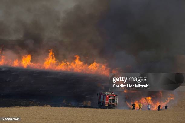 Israeli fire fighters and soldiers attempts to extinguish a fire in a wheat field next to the border with Gaza after it was caused by incendiaries...