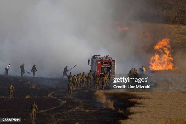 Israeli fire fighters and soldiers attempts to extinguish a fire in a wheat field next to the border with Gaza after it was caused by incendiaries...