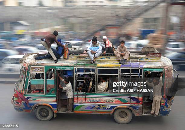 In this picture taken on January 14 a Pakistani commuter tries to find place to sit on top of the Mehran Coach mini-bus passing through Karachi's...