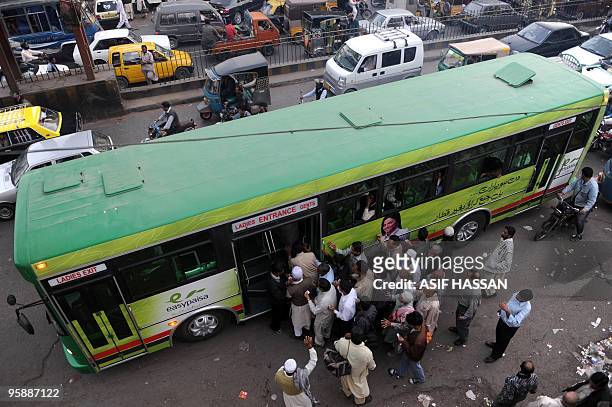 In this picture taken on January 14 Pakistani commuters board a compressed natural gas -powered Green Bus, newly introduced to Karachi, on the city's...