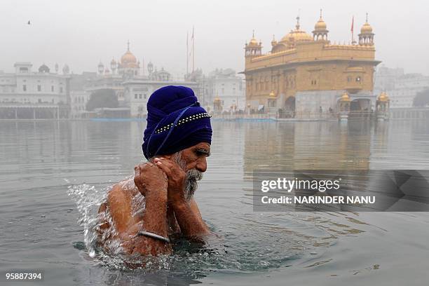 Member of the traditional Sikh religious warriors' Nihang Army bathes in the sarovar - water tank - of The Golden Temple in Amritsar on January 20,...