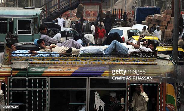 In this picture taken on January 14 Pakistani commuters lie atop a bus driving down Karachi's busiest street, Mohammad Ali Jinnah Road. AFP PHOTO/...