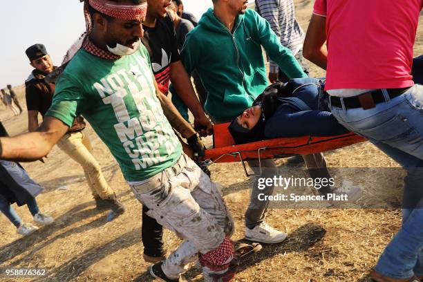 An injured protester is carried to an ambulance at the border fence with Israel on May 15, 2018 in Gaza City, Gaza. Israeli soldiers killed over 50...
