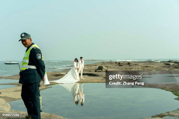 Newly-married couple is taking wedding photograph on beach reef. The number of Chinese marriages has been decreasing since 2013. In 2017, only 10...