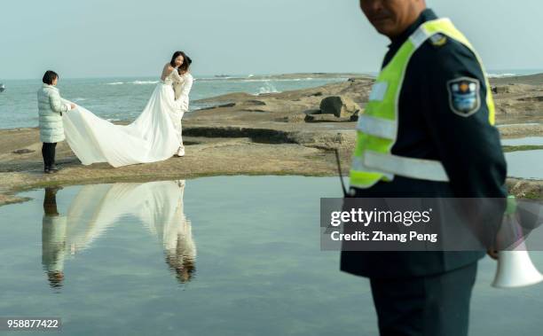 Newly-married couple is taking wedding photograph on beach reef. The number of Chinese marriages has been decreasing since 2013. In 2017, only 10...