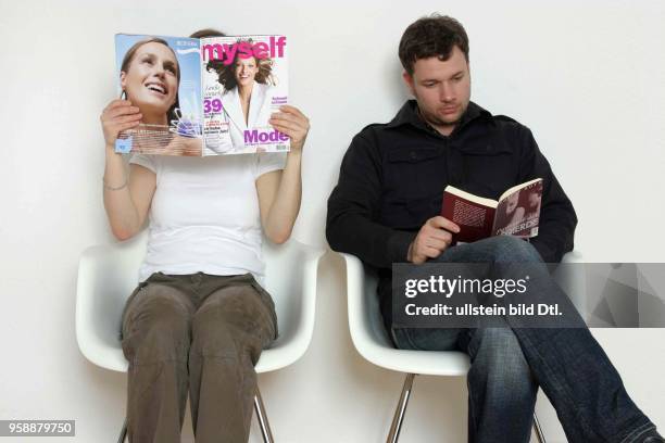 Deutschland, Symbol warten, Wartezimmer, Mann und Frau sitzen im Wartezimmer, sie liest eine Frauenzeitschrift und er liest ein Buch