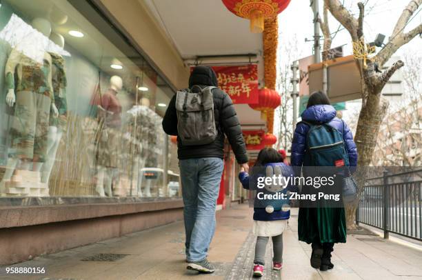 Little girl walk with her parents on the city street. In 2018, with the release of the two child policy, the number of new born population in China...