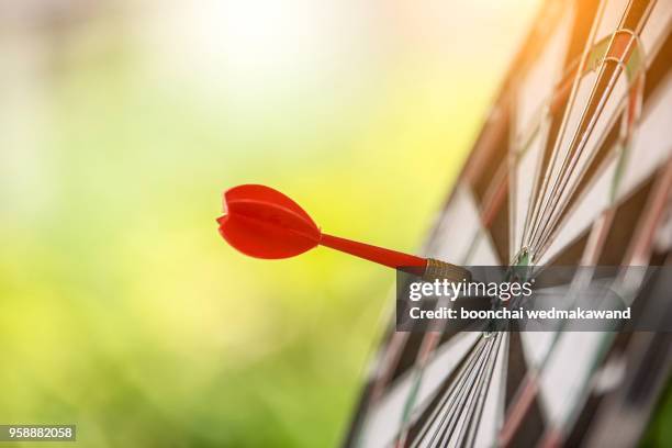 dart arrow hitting in the target center of dartboard - target stockfoto's en -beelden