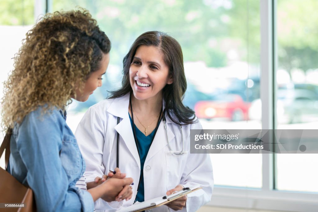 Femme médecin discute quelque chose avec patient jeune métisse