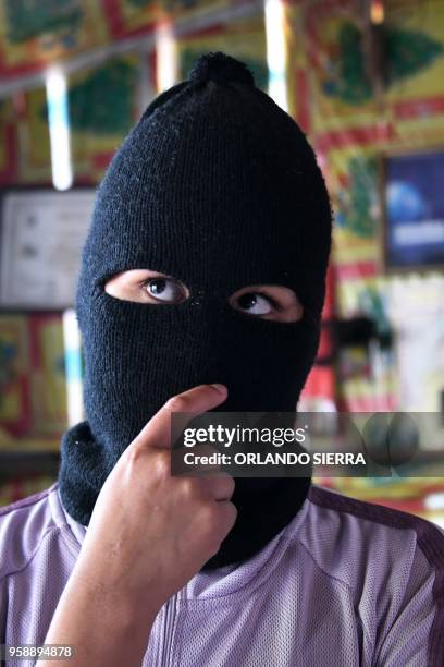 Person wearing a balaclava offers an interview to AFP in the poor neighbourhood of Nueva Capital, on the outskirts of Tegucigalpa, on May 13, 2018. -...