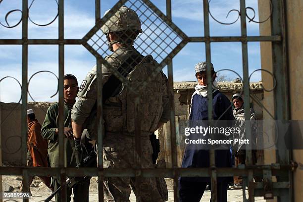 Village children look at a US Army soldier from a Provincial Reconstruction Team on January 20, 2010 in Orgune, Afghanistan. The soldiers, from...