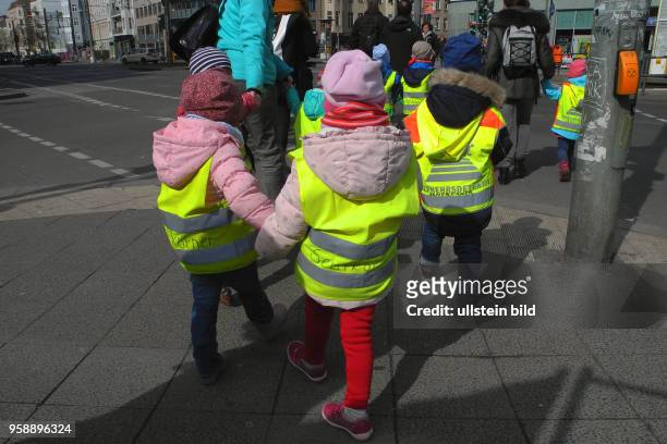 Kindergruppe mit Schutzwesten im Strassenverkehr unterwegs.