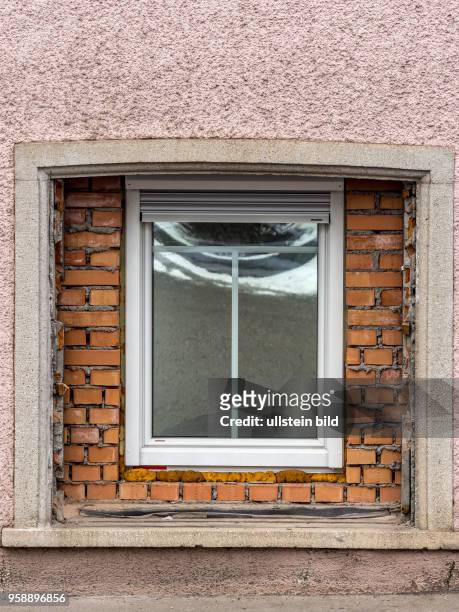 In einem alten Wohnhaus wurde ein großes Fenster durch ein Neues ersetzt. Symbol für Althaussanierung und Wohnraumverbesserung