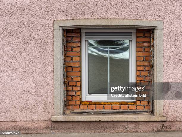 In einem alten Wohnhaus wurde ein großes Fenster durch ein Neues ersetzt. Symbol für Althaussanierung und Wohnraumverbesserung