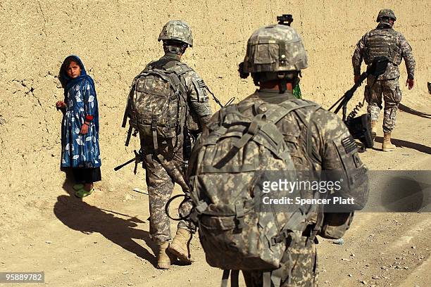 Army soldiers from a Provincial Reconstruction Team walk by a girl on January 20, 2010 in Orgune, Afghanistan. The soldiers, from Forward Operating...