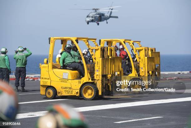 Sailors in forklifts preparing to move cargo on the flight deck of USS Harry S. Truman , Mediterranean Sea, April 28, 2018. Image courtesy United...