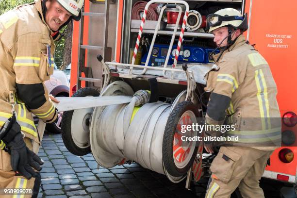 Feuerwehrmänner rollen Schläuche auf die Haspel des Löschfahrzeugs - Einsatz für die Berliner Feuerwehr bei einem vermutlichen Wohungsbrand in...