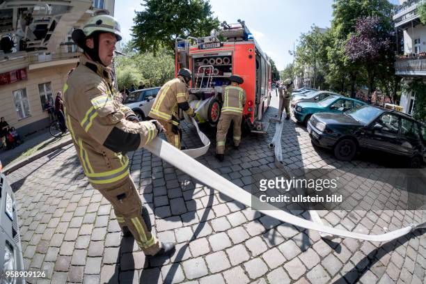 Feuerwehrmänner rollen Schläuche auf die Haspel des Löschfahrzeugs - Einsatz für die Berliner Feuerwehr bei einem vermutlichen Wohungsbrand in...