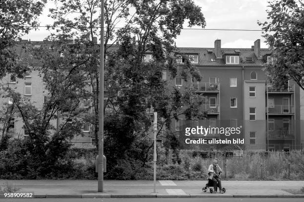 Seniorin warten mit ihrem Rolator an einer Bushaltestelle in der Bernauer Straße in Berlin
