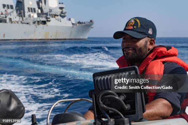 Boatswain's Mate 2nd Class Jeremiah Piquette operating a rigid-hull inflatable boat, USS Winston S Churchill destroyer in the background, April 29,...