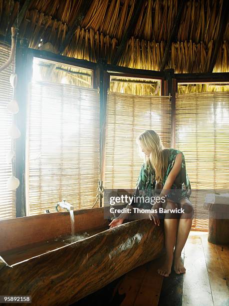 woman running bath in eco lodge bungalow - testing the water stock pictures, royalty-free photos & images