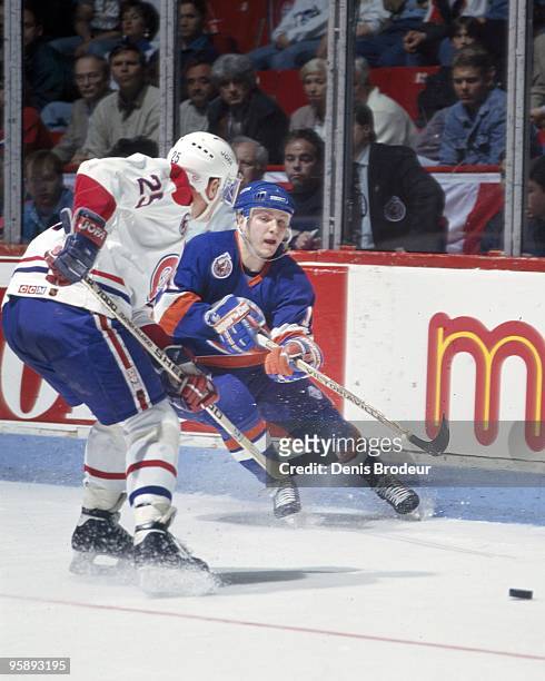 Darius Kasparaitis of the New York Islanders reaches for the puck under pressure by Vincent Damphouse of the Montreal Canadiens in the early 1990's...