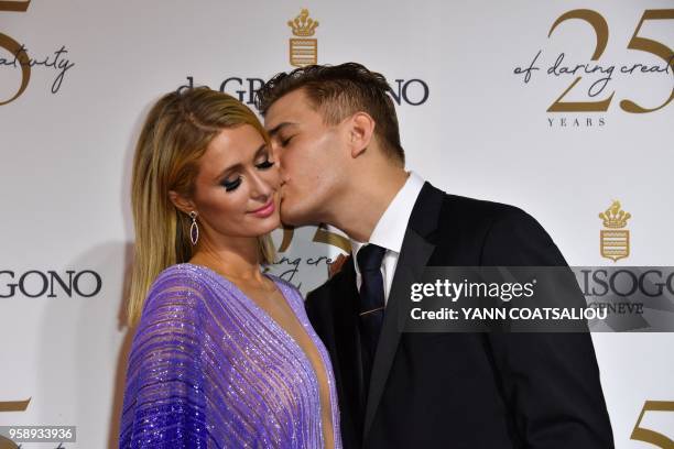 Model Chris Zylka kisses his companion US personality and entrepreneur Paris Hilton during a photocall as they arrive to attend the de Grisogono...