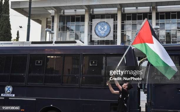 Palestinians who live in Greece wave Palestinian flags at the top of police bus during a protest against the bloodshed along the Gaza border and...