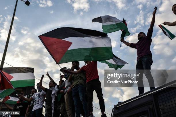 Palestinians who live in Greece wave Palestinian flags at the top of police bus during a protest against the bloodshed along the Gaza border and...