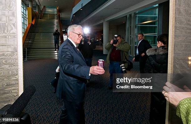 Warren Buffett, chairman and chief executive officer of Berkshire Hathaway Inc., hands a can of Coca-Cola soda to an assistant as he arrives for a...