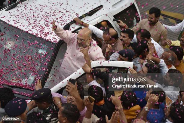 President Amit Shah is showered with flower petals as he arrives at the BJP Headquarters after BJP emerged as the single largest party in Karnataka...