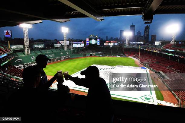 Fans clink their drinks as the game is delayed due to rain before a game between the Boston Red Sox and the Oakland Athletics at Fenway Park on May...