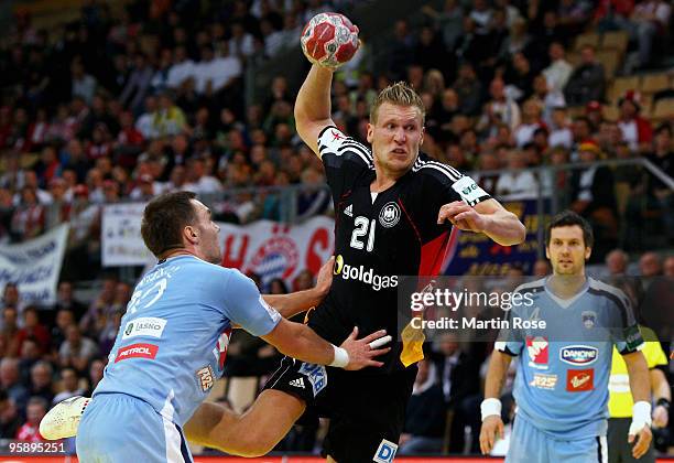 Lars Kaufmann of Germany jumps to pass the ball over Luka Zvizej of Slovenia during the Men's Handball European Championship Group C match between...