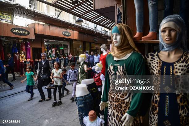 Syrian woman and her children walk on a street near shops in Gaziantep, in the south-west province of Turkey, on May 1, 2018. - In the Turkish city...