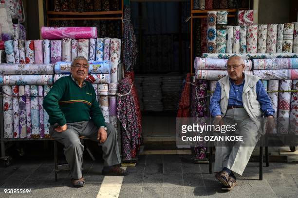 Shop owners sit in front of their shops in Gaziantep, in the south-west province of Turkey, on May 1, 2018. - In the Turkish city of Gaziantep, home...